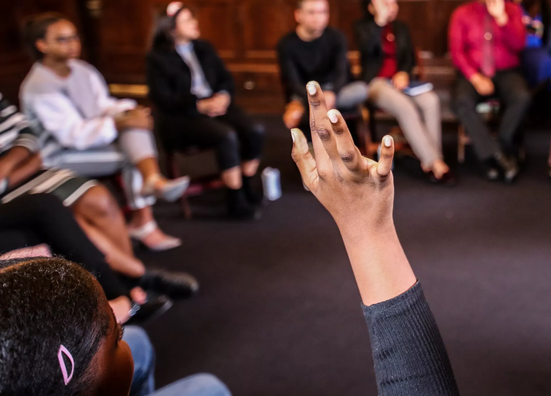 raised hand of young lady at roundtable discussion