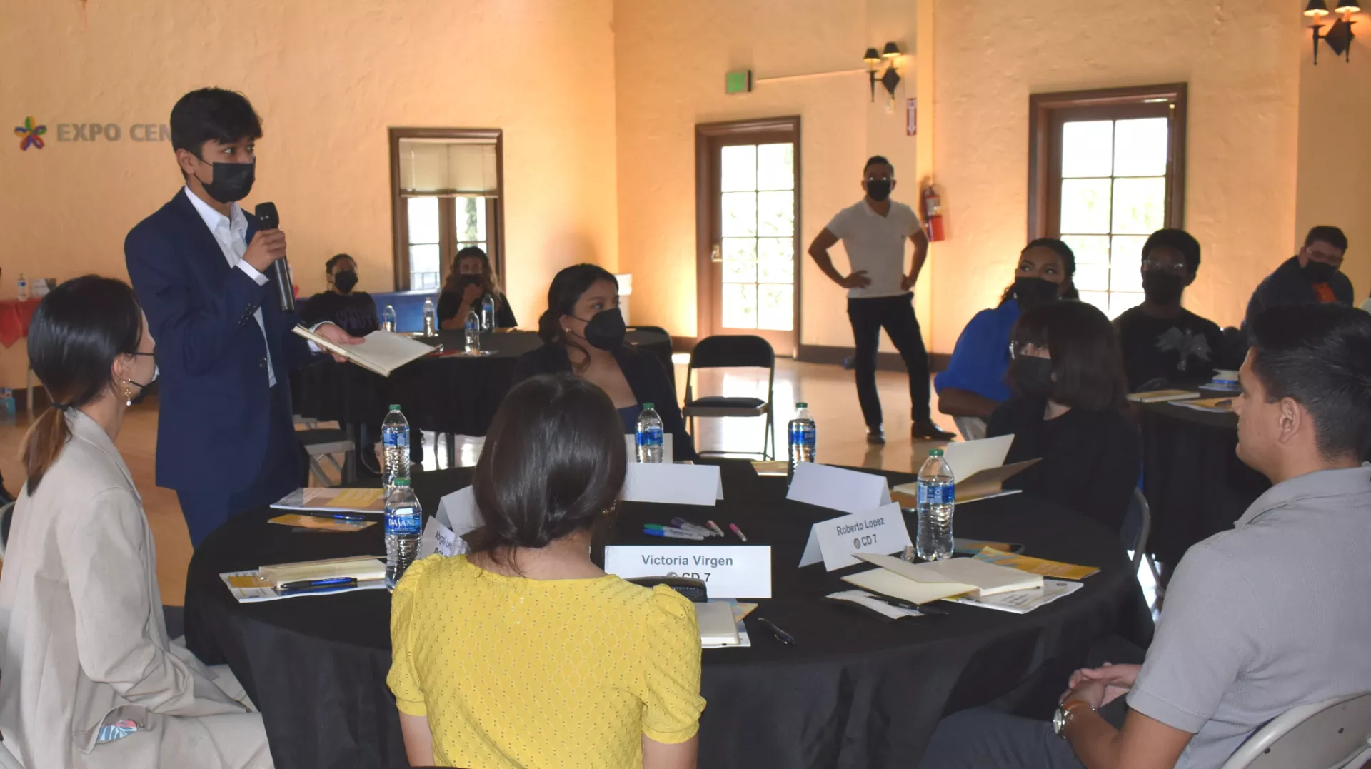 Overview of the youth council during the program orientation with one youth standing speaking. 